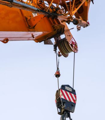 Gru mobile arancione con braccio e ganci su uno sfondo di cielo blu, con tracciati di ritaglio.